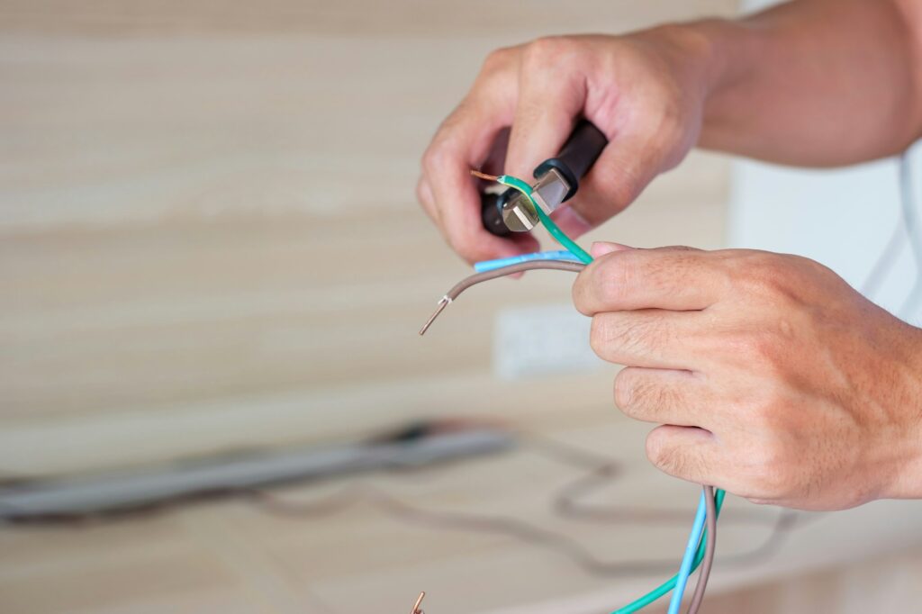 Electrician cuts electrical wires with pliers